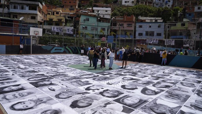 Cara Warga Daerah Kumuh di Venezuela Ubah Stigma Buruk People visit the photographic installation Inside Out, in the San Blas community of Petare, in Caracas, Venezuela, Tuesday, April 12, 2022. The initiative created by the French street artist Jean René, better known as JR, in an effort to overcome the stigma of violence that accompanies the neighborhood. (AP Photo/Ariana Cubillos)