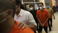 Rico Valentino dengan tangan diborgol terlihat memakai celana pendek dan baju tahanan. Foto: Palevi/detikHOT