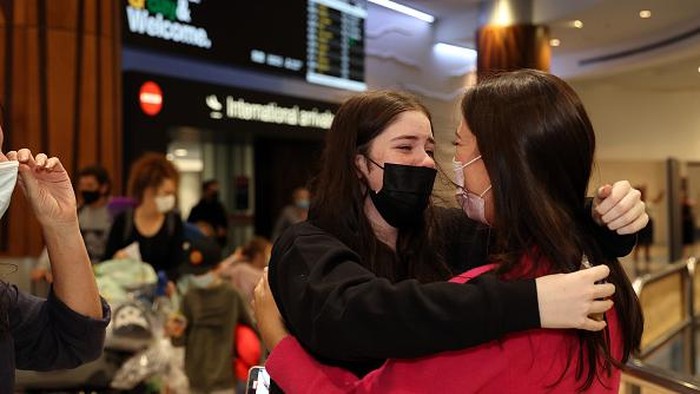 AUCKLAND, NEW ZEALAND  - APRIL 13: Bette-May Waine (C) welcomes her grand daughter Mackenzie Waine (R) and daughter-in-law Lisa Waine (L) and family from Australia for a holiday to Auckland International Airport on April 13, 2022 in Auckland, New Zealand. New Zealand borders reopened to Australian tourists from 11:59 pm on Tuesday 12 April. Vaccinated Australian citizens and permanent residents are eligible for quarantine-free travel with a negative COVID-19 test prior to departure, with tests also taken upon arrival and again on day six in New Zealand. Travellers from countries with visa waiver arrangements such as the United Kingdom will be allowed to come to New Zealand from May 1. (Photo by Fiona Goodall/Getty Images)