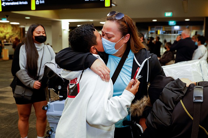 AUCKLAND, NEW ZEALAND  - APRIL 13: Bette-May Waine (C) welcomes her grand daughter Mackenzie Waine (R) and daughter-in-law Lisa Waine (L) and family from Australia for a holiday to Auckland International Airport on April 13, 2022 in Auckland, New Zealand. New Zealand borders reopened to Australian tourists from 11:59 pm on Tuesday 12 April. Vaccinated Australian citizens and permanent residents are eligible for quarantine-free travel with a negative COVID-19 test prior to departure, with tests also taken upon arrival and again on day six in New Zealand. Travellers from countries with visa waiver arrangements such as the United Kingdom will be allowed to come to New Zealand from May 1. (Photo by Fiona Goodall/Getty Images)