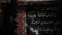 Perajin membentangkan kain batik bermotif ayat suci Al Quran di Mahkota Batik Laweyan, Solo, Jawa Tengah.