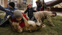 Anak-anak bermain dengan seekor anjing di Bucha, di pinggiran Kyiv, Ukraina.