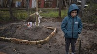 Di halaman rumah, Vlad (6), berdiri di dekat makam ibunya yang meninggal, di pinggiran Kyiv, Ukraina, Senin, (4/4/2022). Ibu Vlad meninggal bulan lalu ketika keluarga itu dipaksa untuk berlindung di ruang bawah tanah selama pendudukan oleh tentara Rusia. Di tengah stres perang, ibunya nyaris tidak makan. Keluarga masih belum mengetahui penyakit apa yang menyebabkan kematiannya.