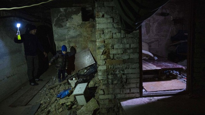 Potret Anak-anak yang Selamat dari Kengerian di Kota Bucha FILE - Vlad, 6, walks with his father Ivan inside a basement where they stayed in Bucha, on the outskirts of Kyiv, Ukraine, April 8, 2022. Vlad's mother died last month when the family was forced to shelter in the basement during the occupation by the Russian army. The family still doesn't know what illness caused her death. (AP Photo/Rodrigo Abd)