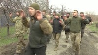 Tentara berjalan dengan tangan terangkat di lokasi yang diberitakan sebagai Mariupol, Ukraina. Dalam potongan gambar yang diambil dari video yang dirilis TV Rusia, Rabu, (13/4/2022), menunjukkan marinir Ukraina menyerah di Mariupol.