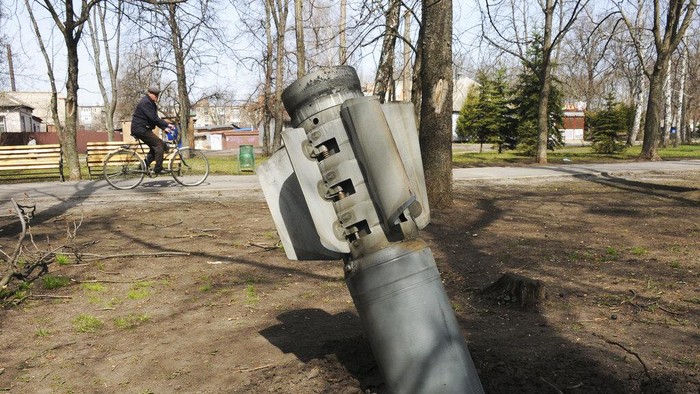 A boy rides a bicycle past a part of a missile leaning against a pole in Chernihiv, Ukraine, Thursday, April 7, 2022. (AP Photo/Evgeniy Maloletka)