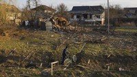 Seorang warga menuntun sepedanya di depan aparteman yang hancur dalam baku tembak di Chernihiv, Ukraina, Kamis (7/4/2022).  (AP Photo/Evgeniy Maloletka)