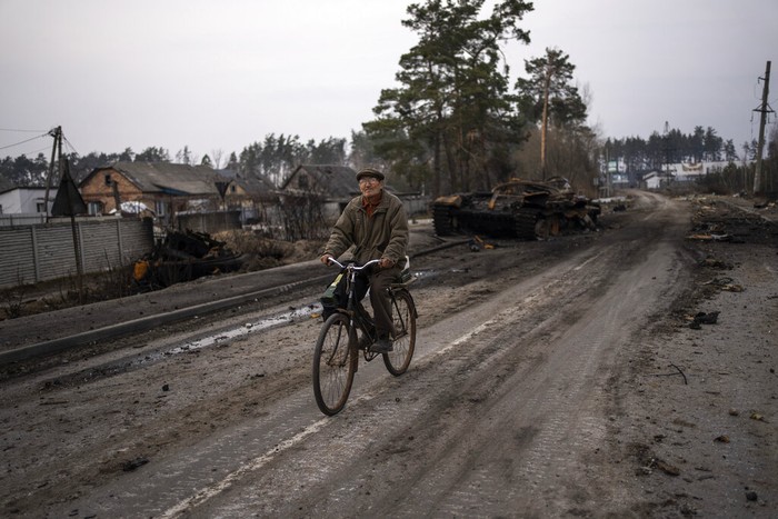 A boy rides a bicycle past a part of a missile leaning against a pole in Chernihiv, Ukraine, Thursday, April 7, 2022. (AP Photo/Evgeniy Maloletka)