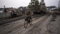 Kakek berusia 81 tahun, Oleksandr, melintas di depan tank Rusia yang hancur di luar kota Ibu Kota Kyiv, Ukraina, Kamis (31/3/2022). Sepeda menjadi andalan warga untuk bepergian di tengah operasi militer Rusia di Ukraina. (AP Photo/Rodrigo Abd)