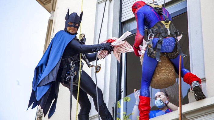 Batman and Spiderman climb down the facade to deliver chocolate eggs for Easter to the children hospitalized in the De Marchi Pediatric Clinic in Milan, Italy, Thursday, April 14, 2022. (LaPresse via AP)