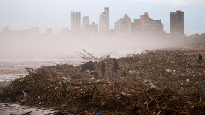 People carry buckets of water filled at broken water mains after water services have been damaged by flooding in Amaoti, Durban, South Africa, April 14, 2022. REUTERS/Rogan Ward