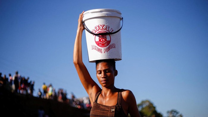 SAFRICA-FLOODS/ People carry buckets of water filled at broken water mains after water services have been damaged by flooding in Amaoti, Durban, South Africa, April 14, 2022. REUTERS/Rogan Ward
