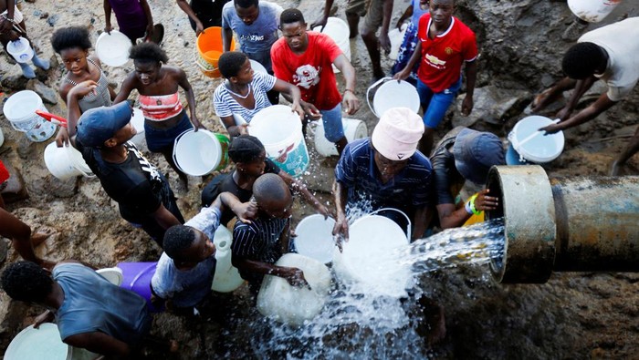 SAFRICA-FLOODS/ People carry buckets of water filled at broken water mains after water services have been damaged by flooding in Amaoti, Durban, South Africa, April 14, 2022. REUTERS/Rogan Ward