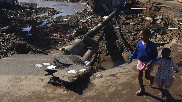 South Africa KwaZulu Natal Floods Children walk on damaged road at an informal settlement in Durban, South Africa, Thursday, April 14, 2022. Heavy rains and flooding have killed at least 341 people in South Africa's eastern KwaZulu-Natal province, including the city of Durban, and more rainstorms are forecast in the coming days. (AP Photo/Str)
