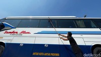 Awak bus membersihkan kendaraan yang terparkir. Belasan unit bus AKAP terparkir di halaman keberangkatan terminal.  