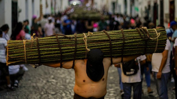 'Yesus' di Meksiko Bawa Seikat Ranting Berduri Saat Prosesi Jalan Salib A penitent carries a bundle of thorny branches during a Holy Week procession in Taxco, Mexico, late Thursday, April 14, 2022. In traditional processions that last from Thursday evening into the early morning hours of Friday, hooded penitents drag chains and shoulder thorny bundles through the streets, as some flog themselves with nail-studded whips meant to bring them closer to God. (AP Photo/Eduardo Verdugo)