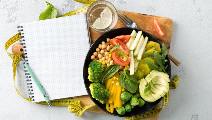 ilustrasi diet Young Asian woman received a box full of colourful and fresh organic groceries ordered online by home doorstep delivery. She is planning to cook a healthy meal in the kitchen at home. Healthy eating lifestyle