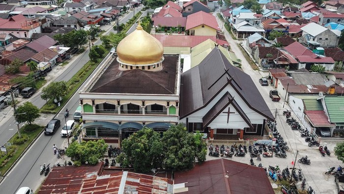 Foto udara Masjid Al Azhar (kiri) dan Gereja Nazaret (kanan) di Jalan Gemini, Palangka Raya, Kalimantan Tengah, Jumat (15/4/2022). Masjid Al Azhar dan Gereja Nazaret tersebut merupakan dua rumah ibadah yang dibangun secara bersamaan pada tahun 1986 dengan letaknya yang berdampingan dan memiliki satu tembok yang menyatu sebagai sebagai simbol toleransi keberagaman antarumat beragama. ANTARA FOTO/Makna Zaezar/nym.