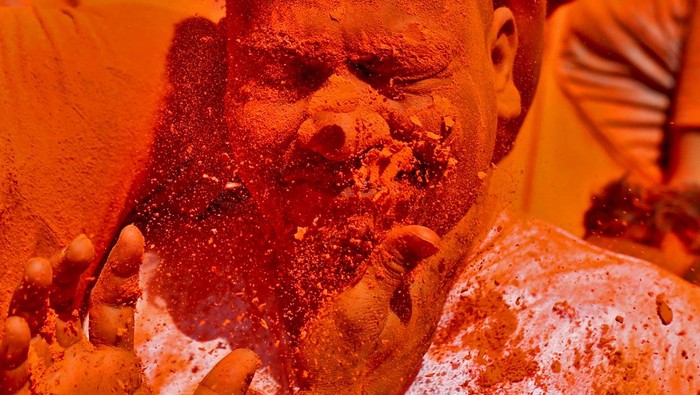 A devotee reacts as vermilion powder is applied on his face during the 