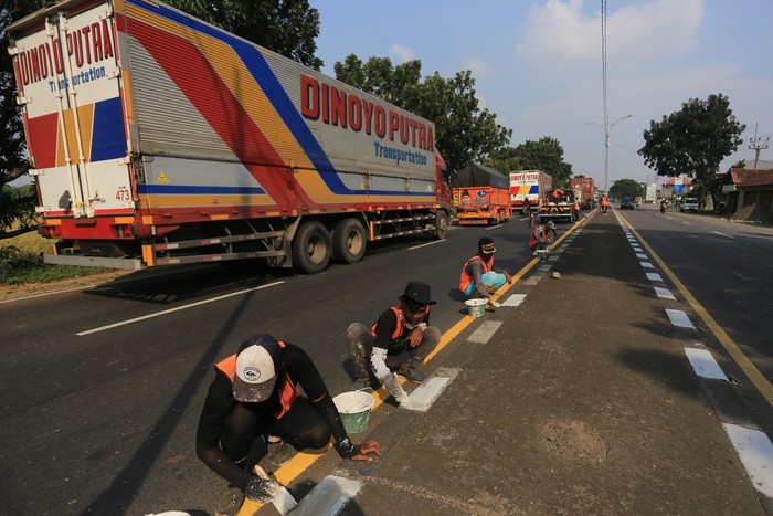 Sejumlah pekerja menyelesaikan pengecatan marka jalan di jalur pantura Widasari, Indramayu, Jawa Barat, Sabtu (16/4/2022). Pengecatan marka jalan tersebut untuk meningkatkan keselamatan dan kenyamanan pemudik yang akan melintas saat mudik Lebaran 2022. ANTARA FOTO/Dedhez Anggara/wsj.