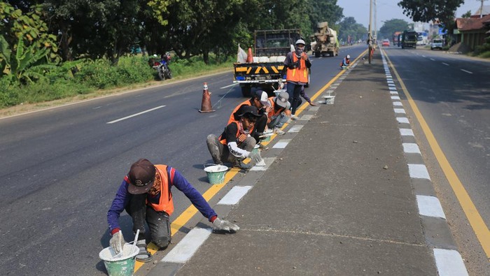 Sejumlah pekerja menyelesaikan pengecatan marka jalan di jalur pantura Widasari, Indramayu, Jawa Barat, Sabtu (16/4/2022). Pengecatan marka jalan tersebut untuk meningkatkan keselamatan dan kenyamanan pemudik yang akan melintas saat mudik Lebaran 2022. ANTARA FOTO/Dedhez Anggara/wsj.