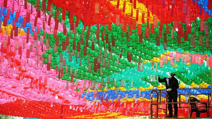 SOUTHKOREA-RELIGION/ A worker attaches prayer petitions to lotus lanterns in preparation for the upcoming birthday of Buddha at a temple in Seoul, South Korea, April 15, 2022. REUTERS/Kim Hong-Ji