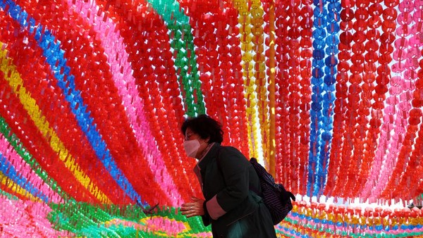 Seorang warga tengah memanjatkan doa di sebuah kuil di Seoul, Korea Selatan, dengan dekorasi warna-warni.