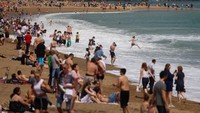 Turis dan penduduk lokal tumpah ruah menikmati indahnya Pantai Barceloneta, Barcelona, Spanyol.