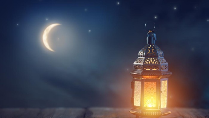 Ornamental Arabic lantern with burning candle glowing at night. Festive greeting card, invitation for Muslim holy month Ramadan Kareem.n