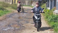 Warga melintasi jalan alternatif yang menghubungkan Kecamatan Majalaya dan Kecamatan Ciparay, Kabupaten Bandung, Jawa Barat, Minggu (17/4/2022).