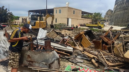 Salah seorang pemilik warung yang terbakar, I Made Ngantra, tampak meminum air kelapa sisa kebakaran di Pantai Melasti, Bali, Minggu (17/4/2022).