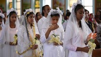 Sejumlah umat Katolik di India memegang lilin dan menunggu untuk menerima komuni suci dari seorang imam di sebuah gereja pada hari Minggu Paskah di Jammu, India. AP Photo/Channi Anand.