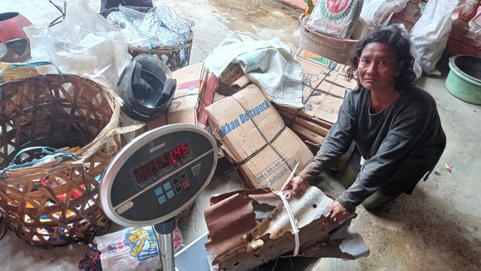 Pemulung di belawan bernama Dedek (40) sedang menimbang sampah yang akan ditabungnya di BSB Belawan.