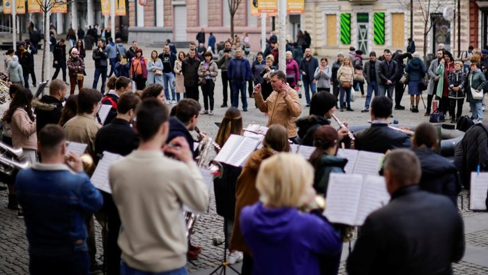 UKRAINE-CRISIS/DNIPRO People watch and listen as Ukrainian musicians take part in a presentation of an orchestra on the street, amid Russia's invasion of Ukraine, in Dnipro, Ukraine April 15, 2022. REUTERS/Ueslei Marcelino
