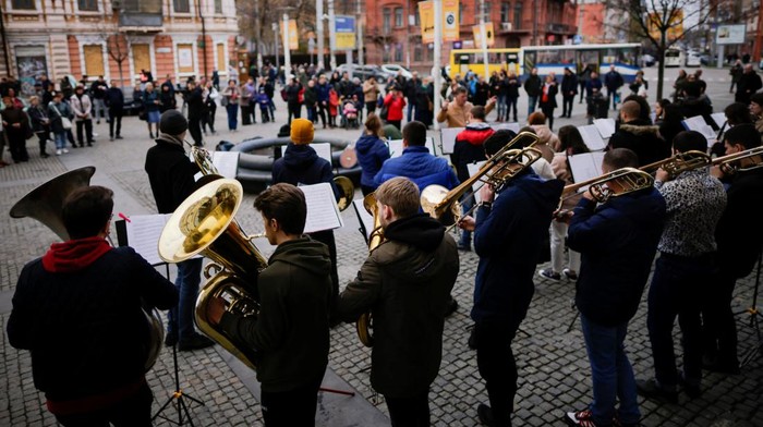 UKRAINE-CRISIS/DNIPRO People watch and listen as Ukrainian musicians take part in a presentation of an orchestra on the street, amid Russia's invasion of Ukraine, in Dnipro, Ukraine April 15, 2022. REUTERS/Ueslei Marcelino
