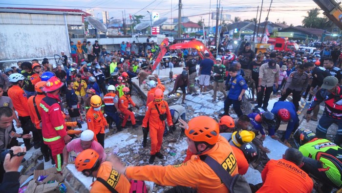 Tim SAR mengevakuasi korban yang terjebak di reruntuhan gedung retail modern Alfamart di Gambut Km 15, Kabupaten Banjar, Kalimantan Selatan, Senin (7/1/2021). Sebanyak 17 orang menjadi korban dalam peristiwa tersebut, lima korban diantaranya berhasil dievakuasi dan hingga kini tim gabungan terdiri dari Basarnas, TNI, POLRI dan relawan dibantu sejumlah alat berat masih terus berupaya melakukan evakuasi korban yang masih terjebak reruntuhan gedung retail modern Alfamart. ANTARA FOTO/Iman Satria/Bay.