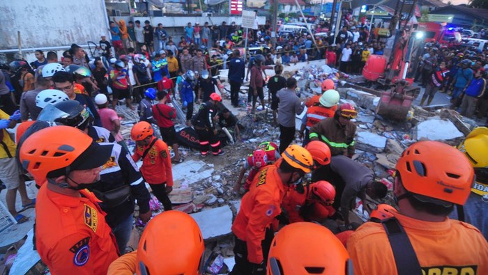 Tim SAR mengevakuasi korban yang terjebak di reruntuhan gedung retail modern Alfamart di Gambut Km 15, Kabupaten Banjar, Kalimantan Selatan, Senin (7/1/2021). Sebanyak 17 orang menjadi korban dalam peristiwa tersebut, lima korban diantaranya berhasil dievakuasi dan hingga kini tim gabungan terdiri dari Basarnas, TNI, POLRI dan relawan dibantu sejumlah alat berat masih terus berupaya melakukan evakuasi korban yang masih terjebak reruntuhan gedung retail modern Alfamart. ANTARA FOTO/Iman Satria/Bay.
