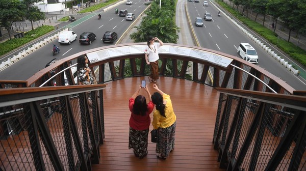 Warga berfoto di Jembatan Penyeberangan Orang (JPO) Pinisi di Jalan Jenderal Sudirman, Jakarta, Sabtu (9/4/2022).