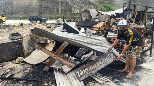 Made Ngantra  membersihkan puing puing sisa kebakaran dari warungnya di Pantai Melasti, Minggu (17/4/2022). (poetri/detikBali)