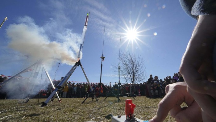 People watch the launch of a model rocket near St. Peter and St. Paul Cathedral during a celebration of the 61st anniversary of Russia's Yuri Gagarin's first manned flight into space, in St. Petersburg, Russia, Sunday, April 17, 2022. (AP Photo/Dmitri Lovetsky)