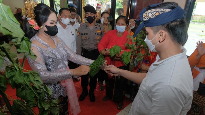 Tahanan Kasus Narkota Ini Menikah di Polresta Denpasar Anggota Polisi berjaga di dekat tahanan kasus narkotika I Wayan Bawa Kartika bersama pasangannya saat melakukan upacara pernikahan secara adat Bali di lobi Polresta Denpasar, Bali, Senin (18/4/2022). Polresta Denpasar memberikan fasilitas untuk menggelar upacara pernikahan bagi tahanan kasus narkotika yang ditangkap pada 3 Desember 2021 dengan barang bukti 163,64 gram sabu-sabu dan 30 butir ekstasi tersebut dengan pengawasan dan penjagaan ketat dari pihak kepolisian. ANTARA FOTO/Nyoman Hendra Wibowo/aww.