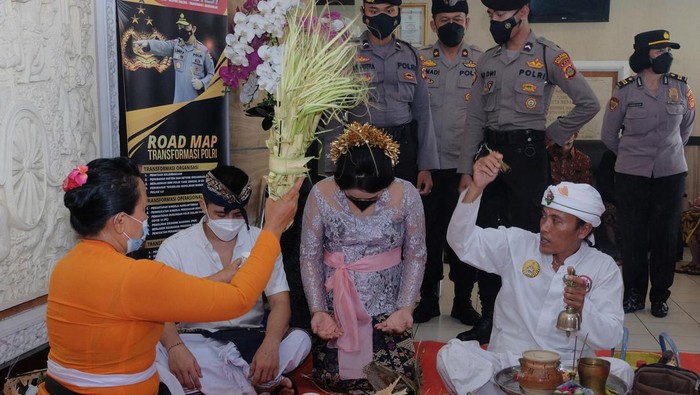 Tahanan Kasus Narkota Ini Menikah di Polresta Denpasar Anggota Polisi berjaga di dekat tahanan kasus narkotika I Wayan Bawa Kartika bersama pasangannya saat melakukan upacara pernikahan secara adat Bali di lobi Polresta Denpasar, Bali, Senin (18/4/2022). Polresta Denpasar memberikan fasilitas untuk menggelar upacara pernikahan bagi tahanan kasus narkotika yang ditangkap pada 3 Desember 2021 dengan barang bukti 163,64 gram sabu-sabu dan 30 butir ekstasi tersebut dengan pengawasan dan penjagaan ketat dari pihak kepolisian. ANTARA FOTO/Nyoman Hendra Wibowo/aww.