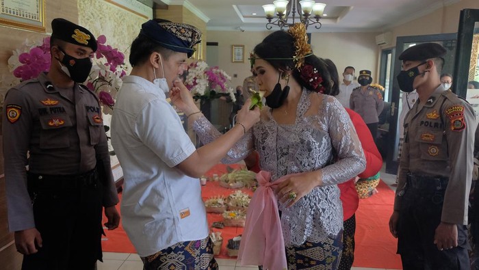 Tahanan Kasus Narkota Ini Menikah di Polresta Denpasar Anggota Polisi berjaga di dekat tahanan kasus narkotika I Wayan Bawa Kartika bersama pasangannya saat melakukan upacara pernikahan secara adat Bali di lobi Polresta Denpasar, Bali, Senin (18/4/2022). Polresta Denpasar memberikan fasilitas untuk menggelar upacara pernikahan bagi tahanan kasus narkotika yang ditangkap pada 3 Desember 2021 dengan barang bukti 163,64 gram sabu-sabu dan 30 butir ekstasi tersebut dengan pengawasan dan penjagaan ketat dari pihak kepolisian. ANTARA FOTO/Nyoman Hendra Wibowo/aww.