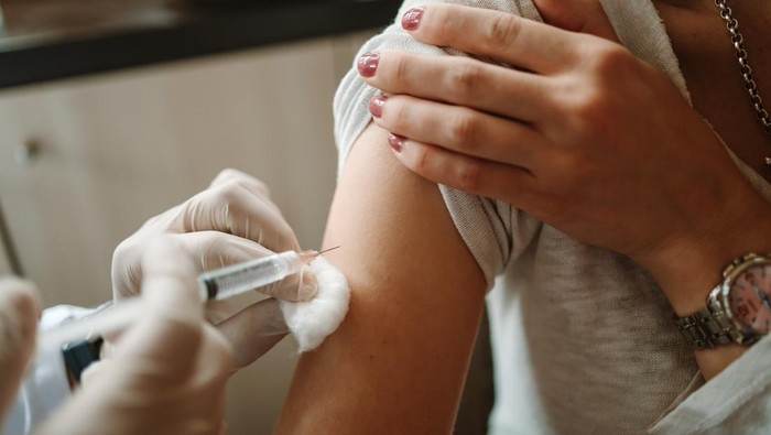 1316009633 Young doctor giving COVID 19 vaccine to young woman at home