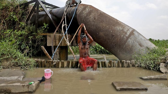 A man bathes with a pipe connected to the valve of a water supply pipe, to cool off during hot weather in Kolkata, India, April 19, 2022. REUTERS/Rupak De Chowdhuri