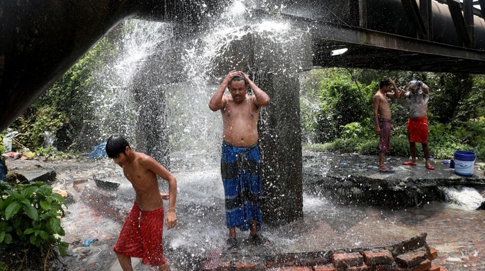 A man bathes with a pipe connected to the valve of a water supply pipe, to cool off during hot weather in Kolkata, India, April 19, 2022. REUTERS/Rupak De Chowdhuri