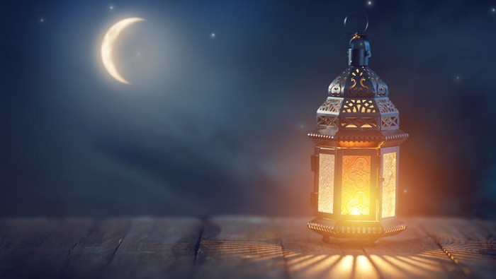 Ornamental Arabic lantern with burning candle glowing at night. Festive greeting card, invitation for Muslim holy month Ramadan Kareem.