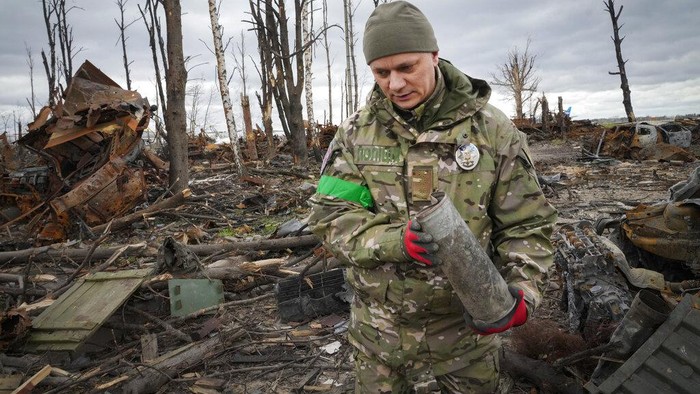 A Ukrainian sapper searches for unexploded explosives as he passes by an Antonov An-225, world's biggest cargo aircraft destroyed during recent fighting between Russian and Ukrainian forces, at the Antonov airport in Hostomel, on the outskirts of Kyiv, Ukraine, Monday, April 18, 2022. (AP Photo/Efrem Lukatsky)