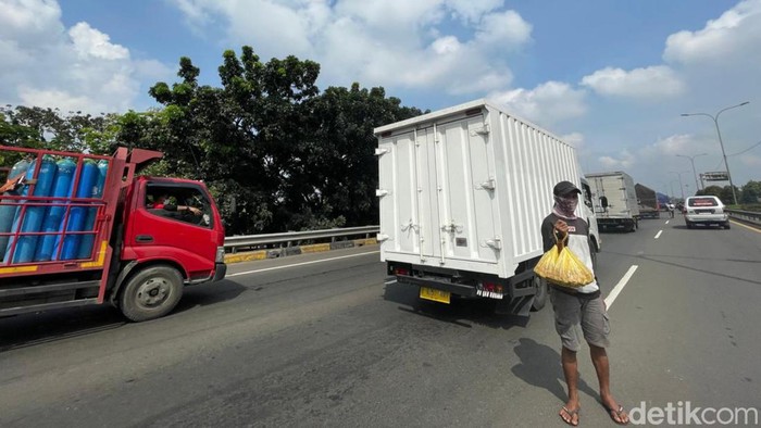 Kemacetan arus kendaraan di ruas jalan tol JORR Jakrta, Selasa (19/04/2022), dimanfaatkan para pedagang asongan yang nekat menerobos masuk menjajakan dagangannya.