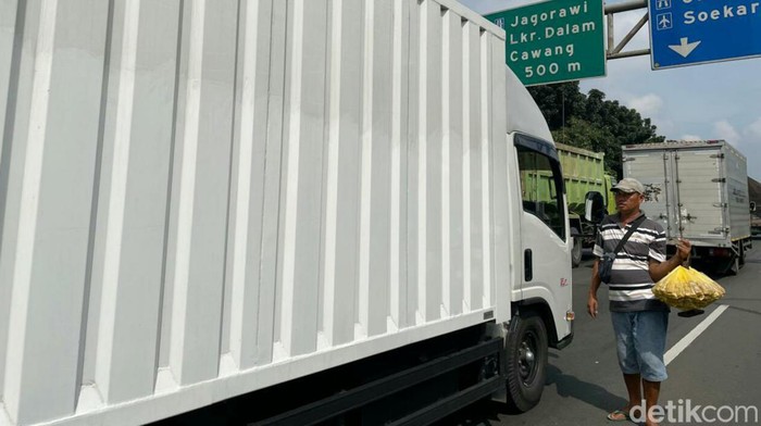 Pedagang Asongan Nekat Dagang di Tengah Kemacetan Tol Jakarta Kemacetan arus kendaraan di ruas jalan tol JORR Jakrta, Selasa (19/04/2022), dimanfaatkan para pedagang asongan yang nekat menerobos masuk menjajakan dagangannya.